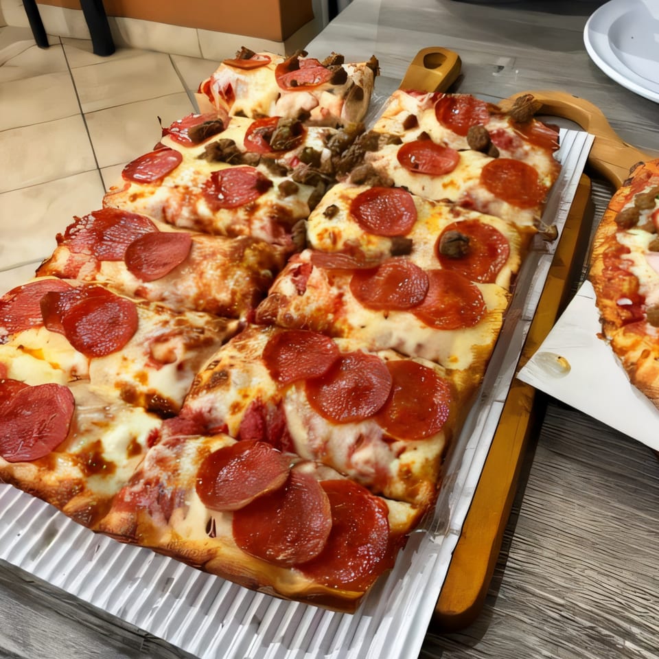Close-up of Pizzano's Buffet pizza slices with pepperoni and sausage on a serving tray.